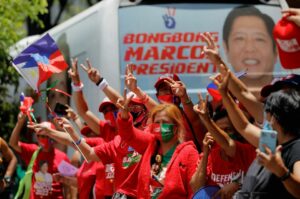 Supporters of presidential candidate Ferdinand “Bongbong” Marcos Jr. gesture and celebrate as partial results of the 2022 national elections show him with a wide lead over rivals, outside the candidate’s headquarters in Mandaluyong City, Philippines, May 10, 2022. REUTERS/Willy Kurniawan.