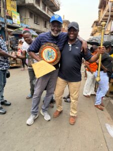 Base Organisation New Chairman, Aminu Majid, left, holding the Base Plaque, the Constitution, with a Base member, right, holding the Staff of Office, in a jubilant mood