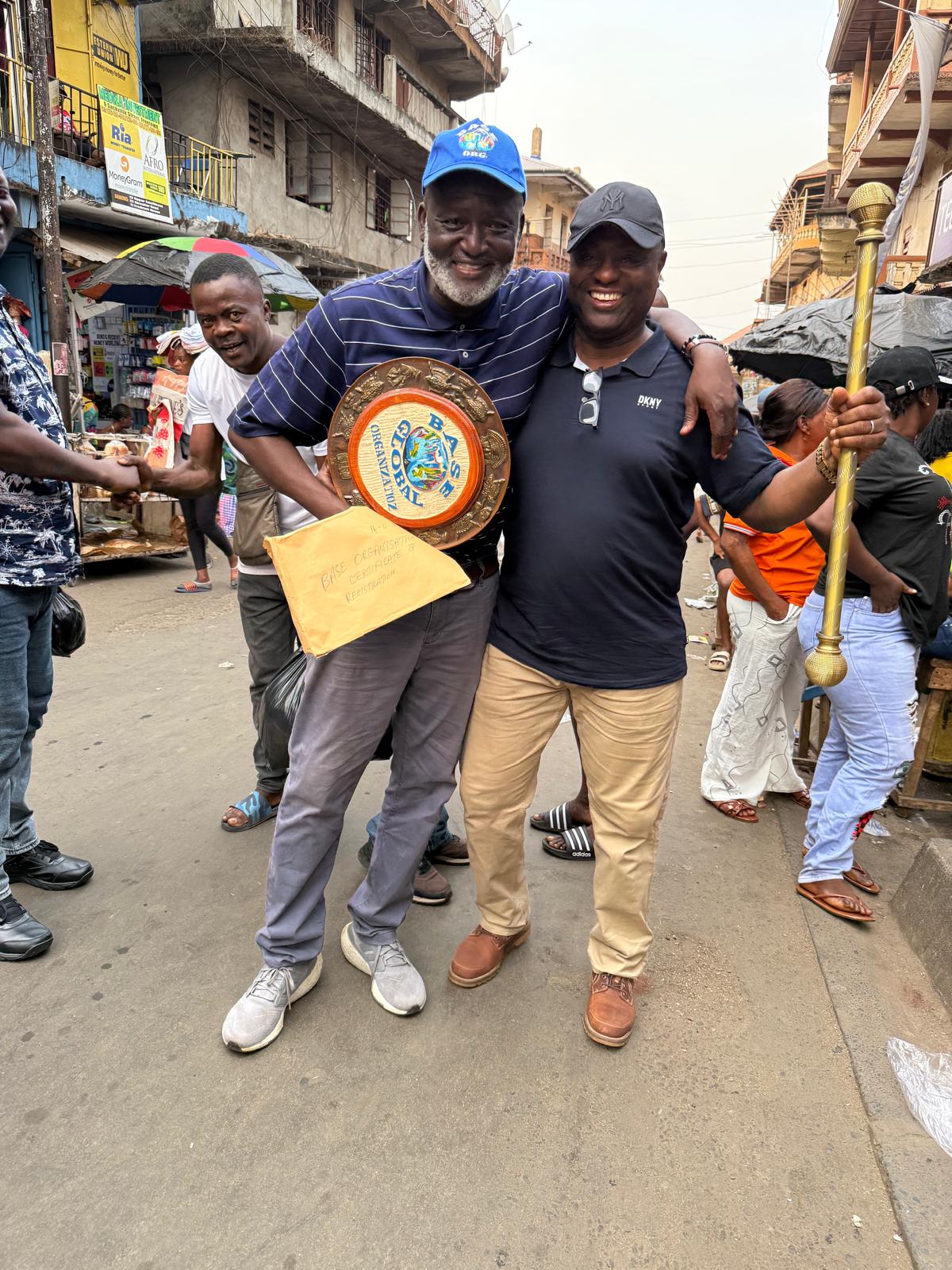 Base Organisation New Chairman, Aminu Majid, left, holding the Base Plaque, the Constitution, with a Base member, right, holding the Staff of Office, in a jubilant mood