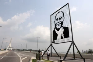 People walk past a portrait of Côte d’Ivoire President Alassane Ouattara at the Alassane Ouattara Bridge in Abidjan, Côte d’Ivoire on January 1, 2025. Luc Gnago/REUTERS
